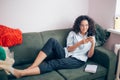 Young woman having a rest with gardget on messy coach indoors Royalty Free Stock Photo