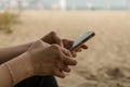 Young woman having rheumatoid arthritis takes a rest sittinng on a bench, looking at her phone at a park. Hands and legs are Royalty Free Stock Photo