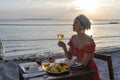 Young woman having romantic dinner in hotel restaurant during sunset near sea waves on the tropical beach, close up Royalty Free Stock Photo