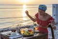 Young woman having romantic dinner in hotel restaurant during sunset near sea waves on the tropical beach, close up Royalty Free Stock Photo