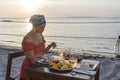 Young woman having romantic dinner in hotel restaurant during sunset near sea waves on the tropical beach, close up Royalty Free Stock Photo