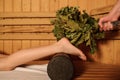 young woman having a russian sauna procedure with bath brooms from oak leaves
