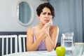 Young woman having toothache and touching cheek, sitting at table Royalty Free Stock Photo