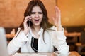 Young woman having unpleasant phone conversation working outside office in her laptop during lunch break drinking hot coffee in Royalty Free Stock Photo