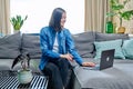 Young woman having video call sitting on sofa at home, using laptop Royalty Free Stock Photo