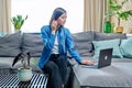 Young woman having video call sitting on sofa at home, using laptop Royalty Free Stock Photo