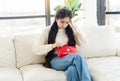 Young woman with headache holding home first aid kit, feeling unwell, sitting on couch Royalty Free Stock Photo