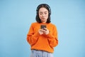 Young woman in headphones and with smartphone listens music, enjoys singing favourite songs in her playlist, blue Royalty Free Stock Photo