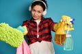 Young woman with headphones stretches and shows to the camera a cloth for cleaning the surface and a spray with detergent Royalty Free Stock Photo