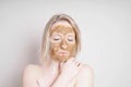 Young woman with healing earth or clay beauty facial mask enjoying wellness treatment