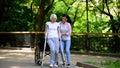 Young woman helping old lady walking on crutches, hip fracture rehabilitation