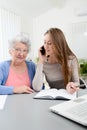 Young woman helping an old senior woman doing paperwork and administrative procedures with laptop computer at home Royalty Free Stock Photo