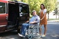 Young woman helping senior man in wheelchair to get into van Royalty Free Stock Photo