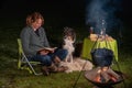 Young woman and her Australian Shepherd outside by a campfire. Reading a book at dusk. Bread, cheese and wine on the Royalty Free Stock Photo
