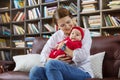 Young woman and her baby daughter on couch in library Royalty Free Stock Photo