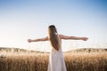Young woman on her back opens her arms in the field feeling free