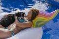 young woman and her border collie dog standing on an inflatable toy unicorn at the swimming pool. Summertime, fun and lifestyle Royalty Free Stock Photo