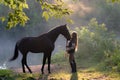 Young woman with her brown horse on a beautiful landscape. Clear lake at morning fog. Sunrise Royalty Free Stock Photo