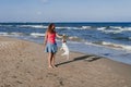 Young woman and her cute small jack russell terrier playing at the beach with a tennis ball. Summer and holidays concept Royalty Free Stock Photo