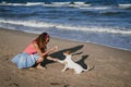 Young woman and her cute small jack russell terrier playing at the beach with a tennis ball. Summer and holidays concept Royalty Free Stock Photo