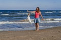 Young woman and her cute small jack russell terrier playing at the beach with a tennis ball. Summer and holidays concept Royalty Free Stock Photo