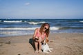 Young woman and her cute small jack russell terrier sitting at the beach enjoying and relaxing. Summer and holidays concept Royalty Free Stock Photo