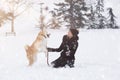 Young woman and her dog akita play in park on snowy day. Royalty Free Stock Photo