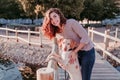 Young woman and her dog outdoors walking by a wood bridge in a park with a lake. sunny day, autumn season Royalty Free Stock Photo