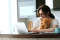 Young woman with her dog working using a laptop at home. Royalty Free Stock Photo