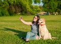 Young woman and her friendly dog taking a selfie at a park