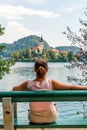 Woman tourist sitting on a bench with her back turned, looking out over Lake Bled in Slovenia. Royalty Free Stock Photo