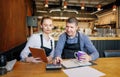 Young woman and her husband sitting at table with tablet and crumpled papers doing accounts for their small restaurant late in Royalty Free Stock Photo