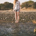 A young woman with her legs naked is standing on the water`s edge Royalty Free Stock Photo