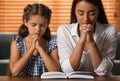 Young woman with her little daughter praying together over Bible at home Royalty Free Stock Photo