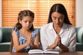 Young woman with her little daughter praying together over Bible at home Royalty Free Stock Photo