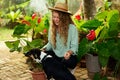 Young woman and her pet dog sitting in garden planting flowers in pots smiles and looks at camera. Female gardener with Royalty Free Stock Photo