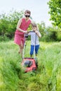 Young woman and her son mowing grass with lawn mower Royalty Free Stock Photo