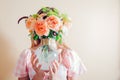 Young woman hides face behind vase with bouquet of flowers. Arrangement with orange roses. Aesthetics in home decor Royalty Free Stock Photo