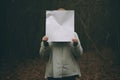 Young woman hiding behind a blank sheet of paper in the forest, An anonymous woman covering her face with paper, AI Generated