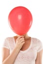 Young woman hiding her face behind balloon