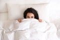 Young woman hiding under warm white blanket in bed, top view Royalty Free Stock Photo