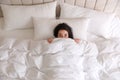 Young woman hiding under warm white blanket in bed, top view Royalty Free Stock Photo