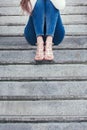 Young woman in high heel shoes and blue jeans on stairs outdoor shot lower body