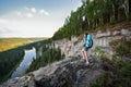 Young woman hiker with backpack standing on cliff and looking far away enjoying beautiful view Royalty Free Stock Photo