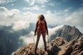 Young woman hiker with backpack standing on top of a mountain and looking into the distance, Extreme woman rock climbing on a Royalty Free Stock Photo