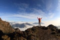 Young woman hiker open arms on mountain peak