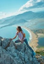 Young woman hiker climbs up on cliff on mountain over beautiful sea coast in Turkey. outdoors activity Royalty Free Stock Photo