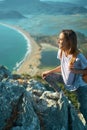 Young woman hiker climbs up on cliff on mountain over beautiful sea coast in Turkey. outdoors activity Royalty Free Stock Photo