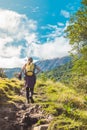 Young woman hiker walking across the path to the mountain in the middle of green nature