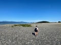 A young woman hiking alone at low tide between Denman Island and JÃ¡ji7em and Kwâulh Marine Park